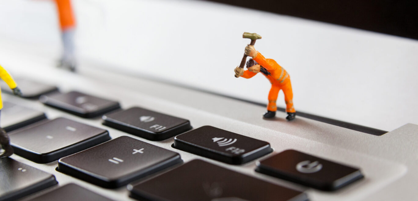 Miniature workmen repairing a laptop keyboard